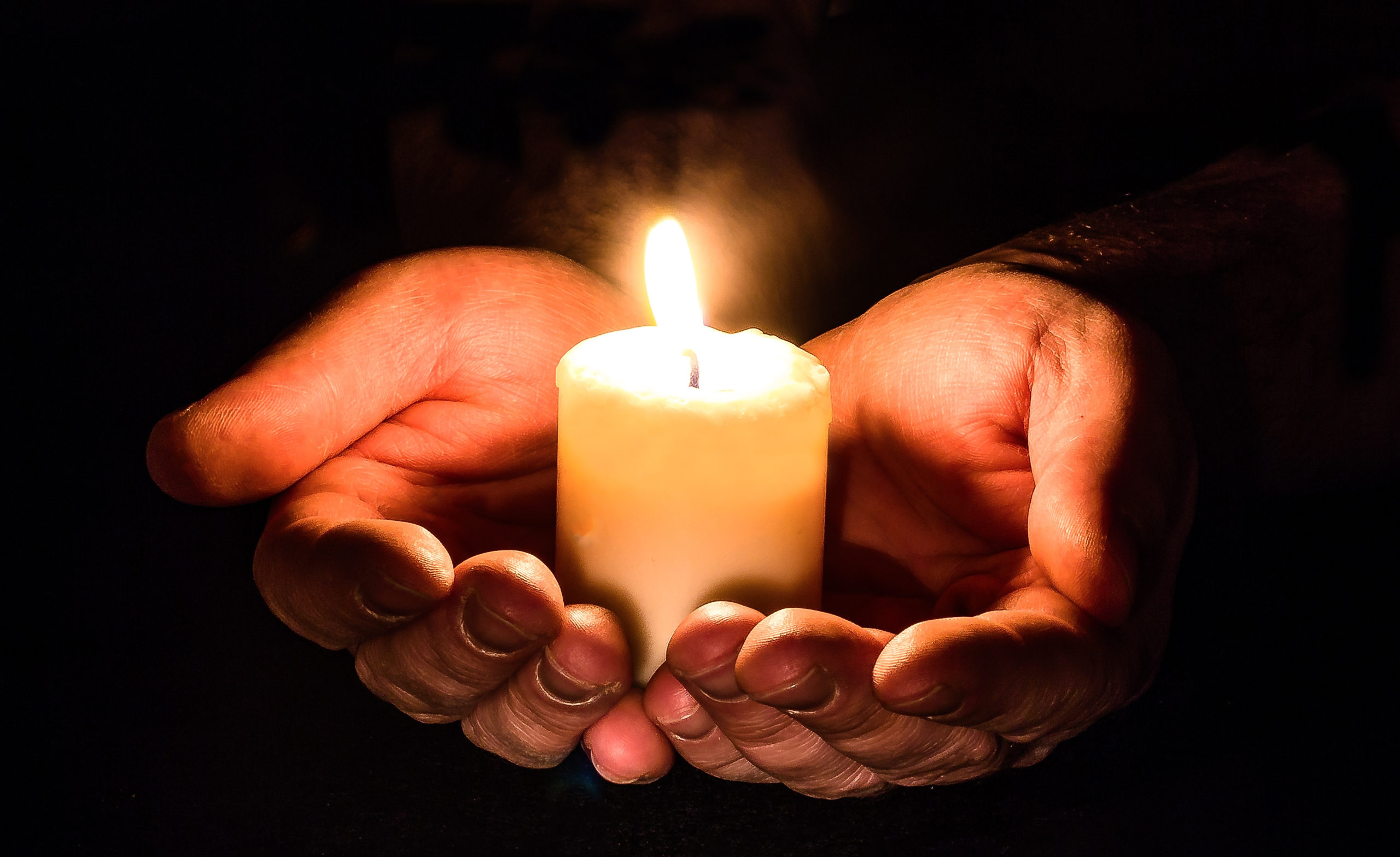 Lit candle cupped hands