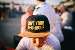 A person in a black ball cap with the words "love your neighbour". 