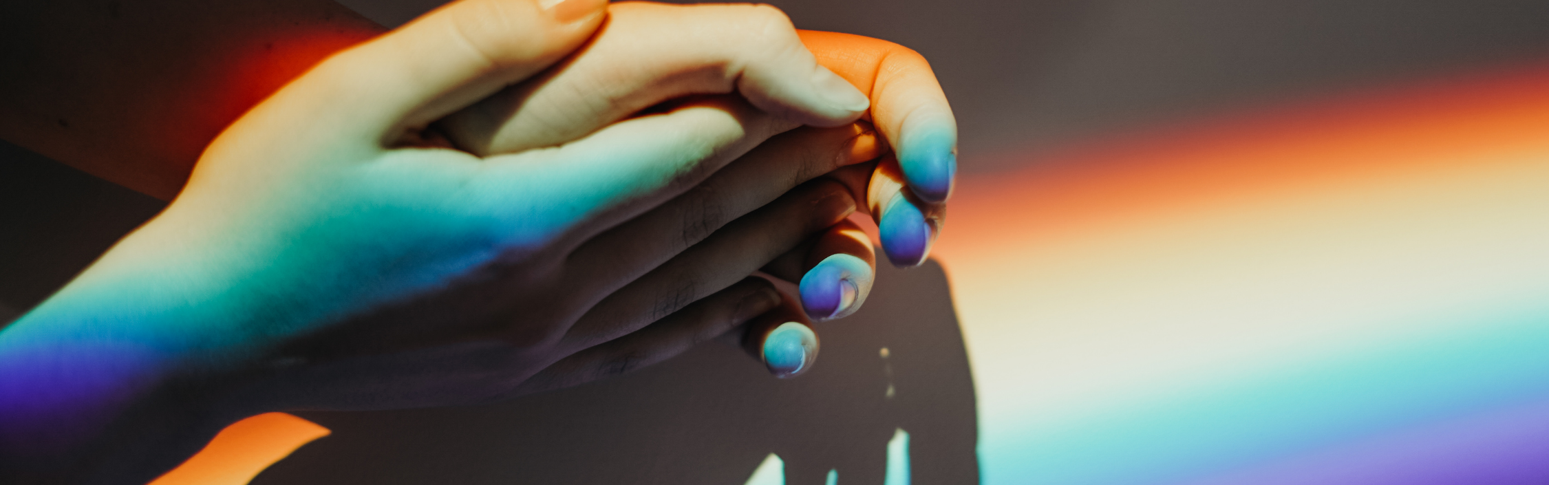 Rainbow light playing over a pair of hands.